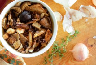 bowl of vegetarian beans with mushroom broth on a table next to green onions and onions