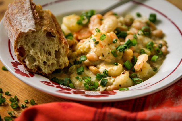 a close up of a plate of cafe reconcile white beans and shrimp