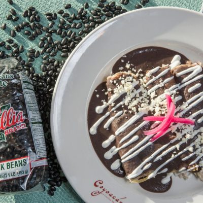 a plate of canal bistro enfrijoladas next to a package of black beans