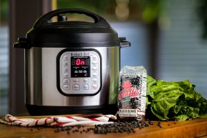 instant pot on next to a bag of camellia black beans and a bundle of herbs