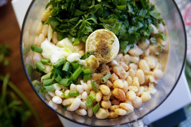 food chopper with white beans, seasoning, green onions and cilantro