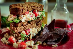white bean tuna sandwich with tomatoes on a plate with chips
