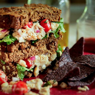 white bean tuna sandwich with tomatoes on a plate with chips