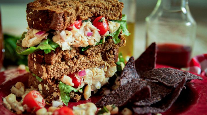 white bean tuna sandwich with tomatoes on a plate with chips