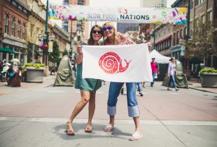 2 woman holding a flag shaped like a snail