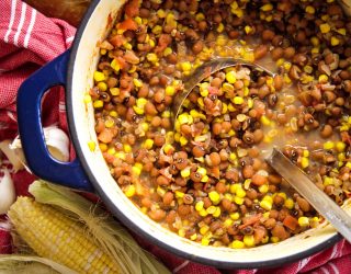 a dutch oven full of stewed tomatoes and corn peas