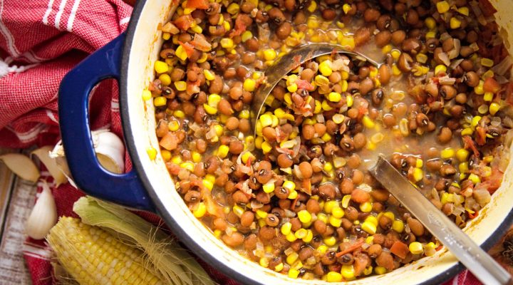 a dutch oven full of stewed tomatoes and corn peas