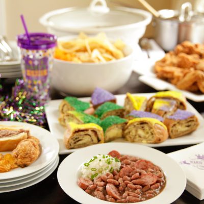 red beans and rice with a side of mashed potatos at a mardi gras party with king cake and bbq chips