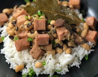 a close up of new years eve black eyed peas with ham chunks and a bayleaf