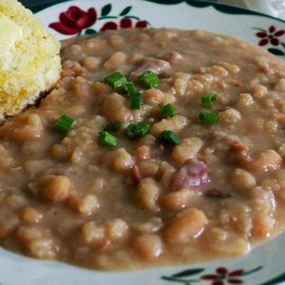great northern beans on a plate with a side of corn bread