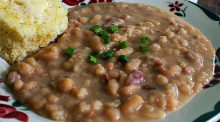 great northern beans on a plate with a side of corn bread