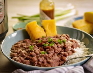 a plate of red beans and rice with a side of cornbread