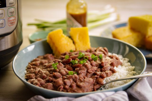 a plate of red beans and rice with a side of cornbread