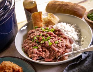 a plate of red beans and rice with a side of corn bread