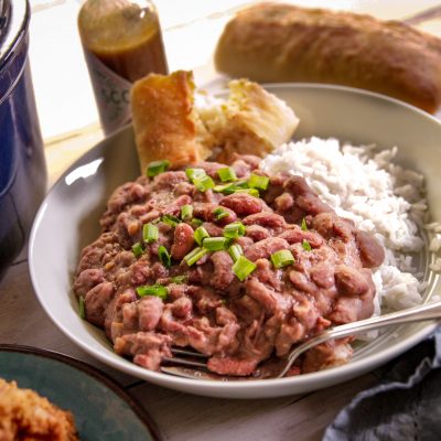 a plate of red beans and rice with a side of corn bread