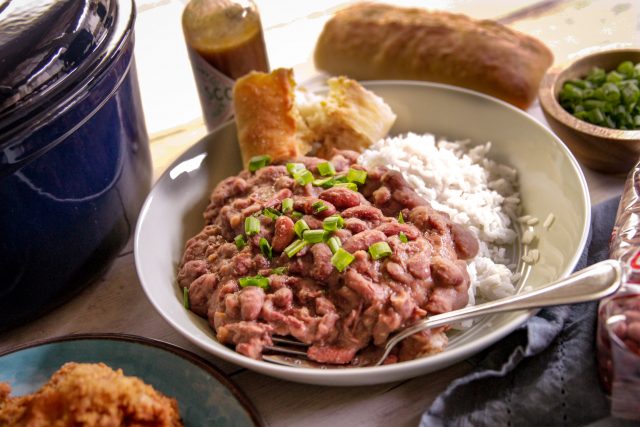 a plate of red beans and rice with a side of corn bread