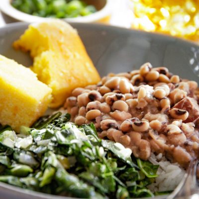 a plate of blackeye peas and a side of collard greens and corn bread