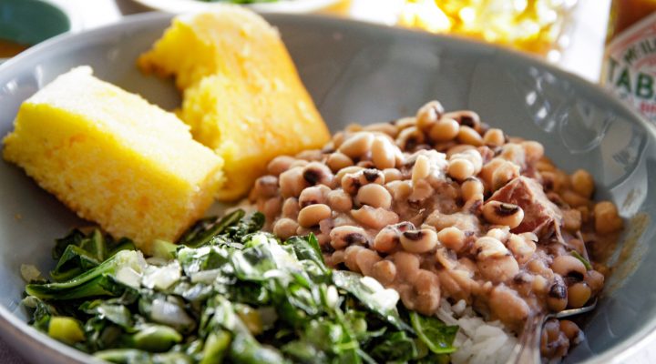 a plate of blackeye peas and a side of collard greens and corn bread