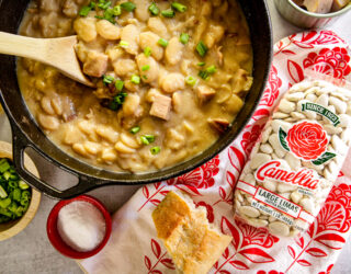 Simple Lima Beans inside a cast iron pan and a bag of large lima beans placed on the side