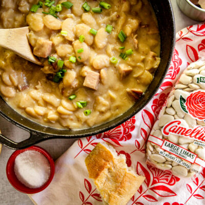 Simple Lima Beans inside a cast iron pan and a bag of large lima beans placed on the side