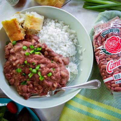 Plated red beans and rice with french bread. A bag of 1 pound red kidney beans on the side.