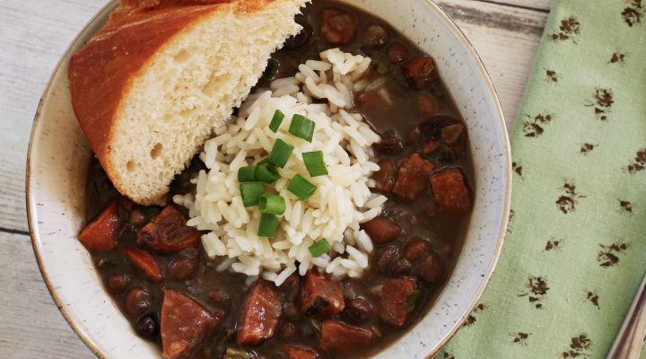 a bowl of crowder peas with smoked pork sausage and green onions with a side of corn bread