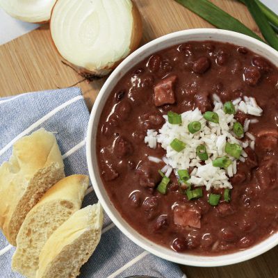 small red beans and rice in a bowl next to corn brean and half an onion