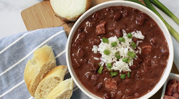 small red beans and rice in a bowl next to corn brean and half an onion