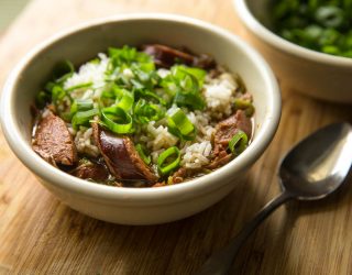 a small bowl of pableaux gumbo with sausage, rice, and green onions