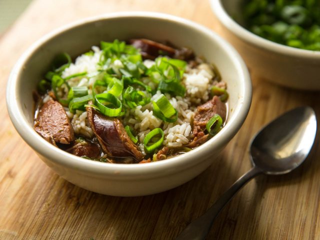 a small bowl of pableaux gumbo with sausage, rice, and green onions