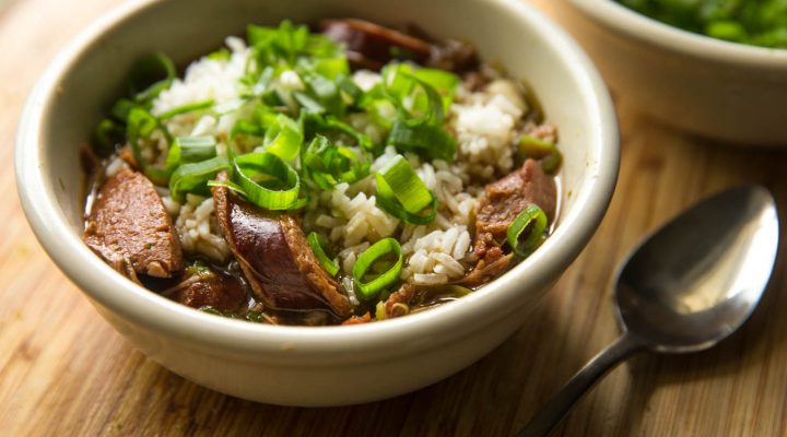 a small bowl of pableaux gumbo with sausage, rice, and green onions