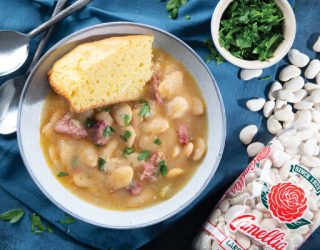 a bowl of Southern Large Limas and sausage with a side of corn bread on top next to a package of camellia brand large lima beans