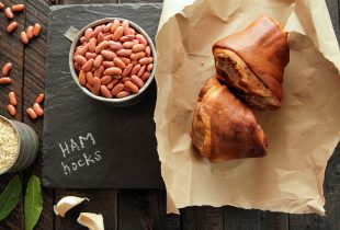 hamhocks and a cup of red beans on a charcoal cut board