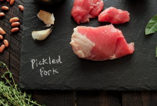 a piece of pickled pork on a charcoal cutting board with the text pickled pork written in chalk