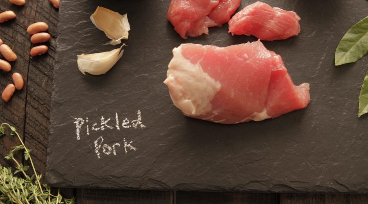 a charcoal cutboard with pickled pork with chalk writting saying pickled pork