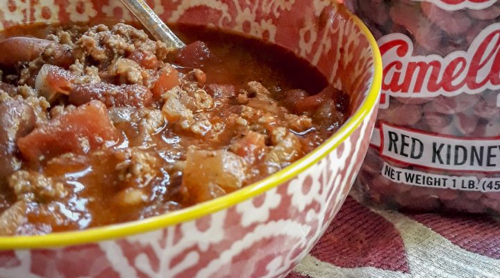 bowl of chili with can of seasoning and bag of beans