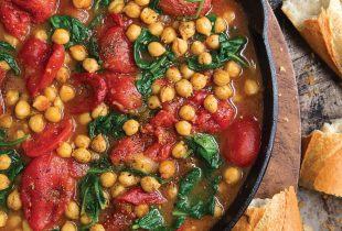 a cast iron pot filled with braised chickpeas and tomatoes