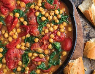 a cast iron pot filled with braised chickpeas and tomatoes