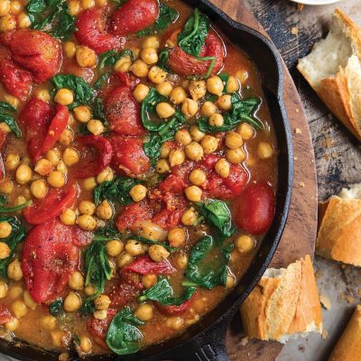 a cast iron pot filled with braised chickpeas and tomatoes
