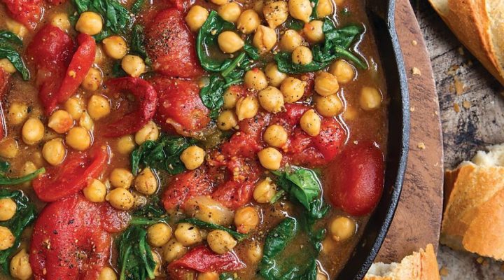 a cast iron pot filled with braised chickpeas and tomatoes