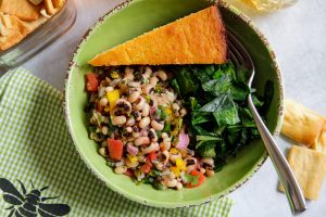 a bowl of cowboy caviar with greens and cornbread