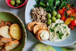 a plate of white bean hummas with a side of rice and assorted greens