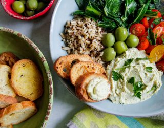 a plate of white bean hummas with a side of rice and assorted greens