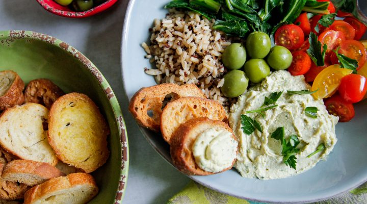 a plate of white bean hummas with a side of rice and assorted greens