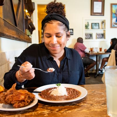 smile customer eating red beans and rice with a side of chicken and corn bread at willie mae