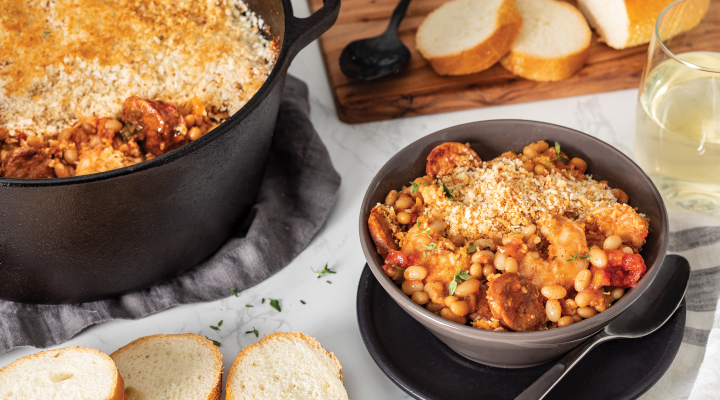 a bowl of Camellia's Shrimp, Andouille and White Bean Cassoulet next to a dutch oven