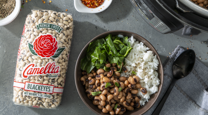 a bowl of black eyes and white rice witth a small green side salad next to a package of camellia brand package of blackeyes