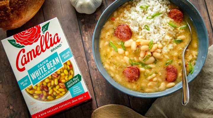 box of Camellia cajun white bean seasoning next to blue bowl with finished white beans meal on wood table