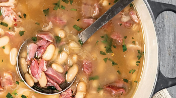 a dutch oven pot filled with white bean stew and hamhock