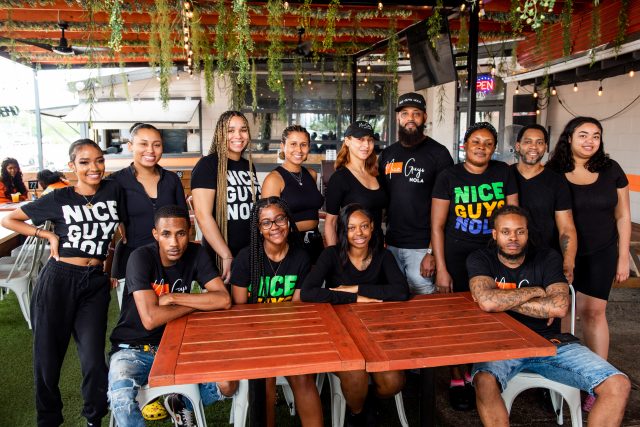 The wait staff posing for a picture outdoors.